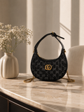 Noir crescent mini shoulder bag with gold chain on marble console